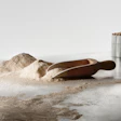 Scattered flour with wooden scoop and metal containers on light surface