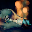 Close-up of a glowing light bulb with blurred warm lights in background